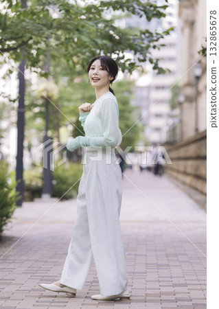 30 多歲的微笑女士在城裡散步 132865678