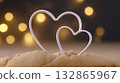 Two heart-shaped metal cookie cutters placed on raw dough, with warm bokeh lights in the background suggesting romance or holidays.  132865967