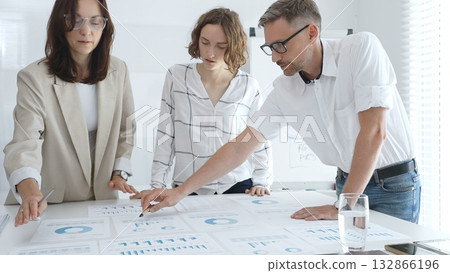 Professional team analyzing financial data, corporate colleagues carefully examining charts and graphs in modern workplace. Business people concept Professional team analyzing financial data, corporate colleagues carefully examining charts and graphs in modern workplace. Business people concept 132866196