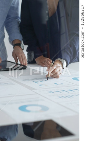 Professional team reviewing financial documents, pointing at charts on desk, collaborating to analyze data and strategize business growth. Business people concept 132866217