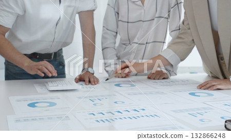 Professional team reviewing financial charts and graphs, working together in modern office space, developing strategic improvements. Business people concept 132866248