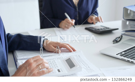 Close up of male accountant hands using calculator and collaborating with female colleague in a modern office, calculating taxes and analyzing financial data. Audit and taxes in business Close up of male accountant hands using calculator and collaborating with female colleague in a modern office, calculating taxes and analyzing financial data. Audit and taxes in business 132866249