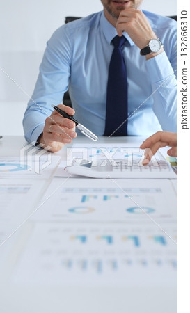 Corporate team of business professionals reviewing financial charts and graphs during meeting, analyzing data strategy, discussing growth performance, and planning market goals. Businesspeople at work Corporate team of business professionals reviewing financial charts and graphs during meeting, analyzing data strategy, discussing growth performance, and planning market goals. Businesspeople at work 132866310