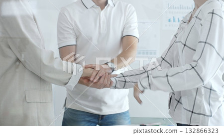 Business people joining hands in a stack, symbolizing strong teamwork and collaboration toward shared goals 132866323