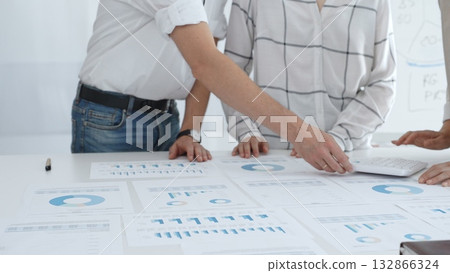 Professional team reviewing financial charts and graphs, working together in modern office environment, discussing strategic improvements. Business people concept 132866324