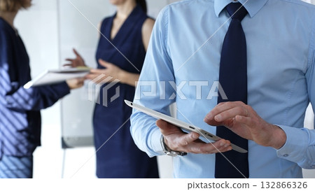 Business professional hands using a tablet during an office meeting, collaborating and discussing new strategies with colleagues in a corporate environment 132866326