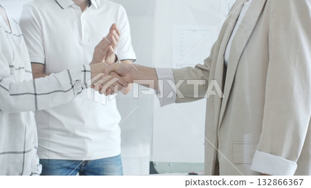 Two businesswomen shaking hands in a modern office, celebrating a successful deal while a male colleague applauds their achievement in office. Business people concept Two businesswomen shaking hands in a modern office, celebrating a successful deal while a male colleague applauds their achievement in office. Business people concept 132866367