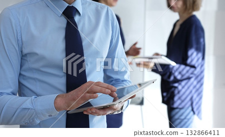 Businessman hands holding and using a digital tablet for work, navigating information and checking data during a modern corporate meeting Businessman hands holding and using a digital tablet for work, navigating information and checking data during a modern corporate meeting 132866411