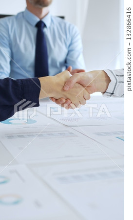 Business woman partners are shaking hands in office with financial charts, laptop and reports on table, symbolizing success, teamwork and agreement. Handshake concept Business woman partners are shaking hands in office with financial charts, laptop and reports on table, symbolizing success, teamwork and agreement. Handshake concept 132866416