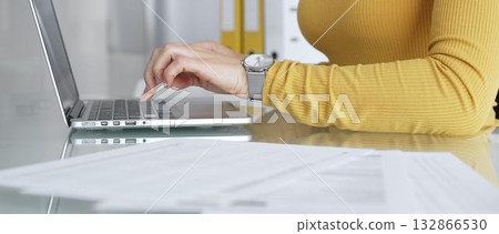 Woman working on laptop, typing on keyboard in office, managing business documents on desk, focusing on digital marketing communication and online data entry Woman working on laptop, typing on keyboard in office, managing business documents on desk, focusing on digital marketing communication and online data entry 132866530