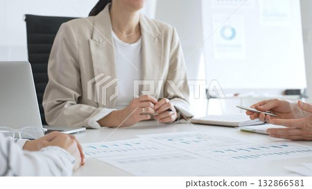 Business team analyzing financial data and discussing marketing strategy during a meeting in the office, businesswoman pointing at charts and explaining strategy to colleagues 132866581
