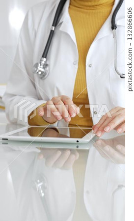 Doctor using tablet, working in clinic office, health care professional analyzing electronic medical records data. Medicine, healthcare and science concept Doctor using tablet, working in clinic office, health care professional analyzing electronic medical records data. Medicine, healthcare and science concept 132866606
