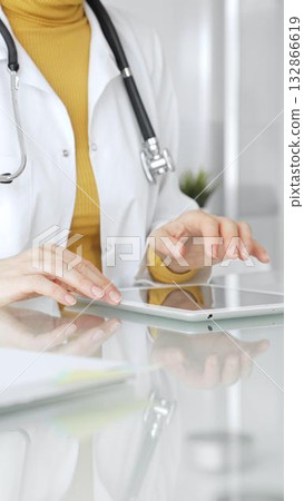 Doctor using tablet, working in clinic office, health care professional analyzing electronic medical records data. Medicine, healthcare and science concept Doctor using tablet, working in clinic office, health care professional analyzing electronic medical records data. Medicine, healthcare and science concept 132866619