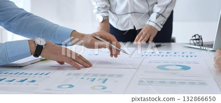 Business team discussing financial charts and strategy with graphs and data analysis documents on office desk during meeting for planning and corporate decisions Business team discussing financial charts and strategy with graphs and data analysis documents on office desk during meeting for planning and corporate decisions 132866650