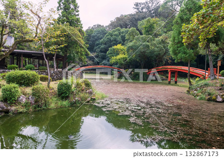 Red curve arching bridge over pond and Japanese garden of Usa shrine , Oita Red curve arching bridge over pond and Japanese garden of Usa shrine , Oita 132867173