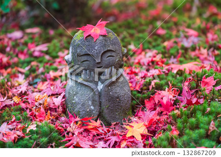 Smile Jizo Buddha stone statue with red maple leaf, Enko-ji temple, Kyoto 132867209
