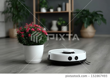 Vacuum robot curling into resting position beside a potted plant in a modern living room 132867493