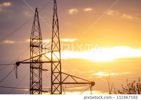 Sunset casts warm light on electrical pylons and clouds 132867588