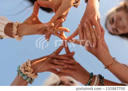 Hands, connection, sky. Group of diverse friends forming a star shape with hands against a clear blue sky, symbolizing unity and teamwork. Hands, connection, sky. Group of diverse friends forming a star shape with hands against a clear blue sky, symbolizing unity and teamwork. 132867708