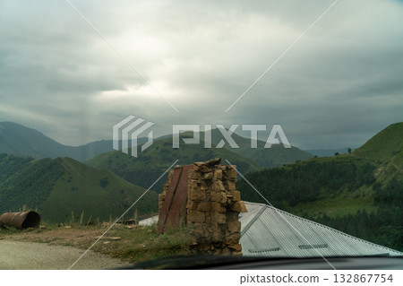 A mountain range with a cloudy sky and a building in the distance A mountain range with a cloudy sky and a building in the distance 132867754