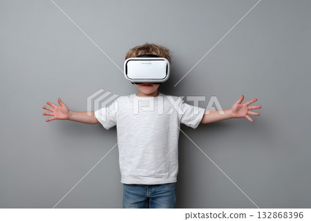 Child explores virtual reality in a gray room with arms outstretched during an immersive experience 132868396