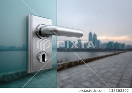 Minimalist glass door handle with cityscape view in the background during dusk hours 132868592