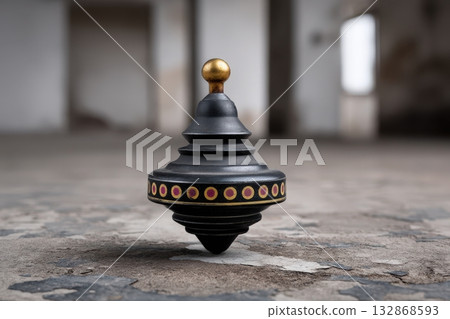 A tin spinning top gracefully rotates on a textured floor, evoking memories of childhood play 132868593