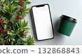 Stylish mockup showcasing a blank smartphone alongside a coffee cup and decorative foliage 132868843