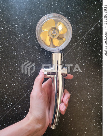 Holding a Golden Turbine Shower Head 132868932