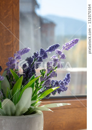 Artificial plant purple flower on window sill 132870364