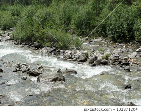 A turbulent stream of clear water from the high mountains continues its movement over the rocks like a mountain stream. 132871204