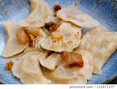 The hands of a senior home cook hold a plate with a national Slovak dish - Bryndzove Pirohy. 132871375