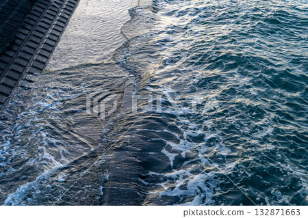 Waves crashing against the seawall 132871663