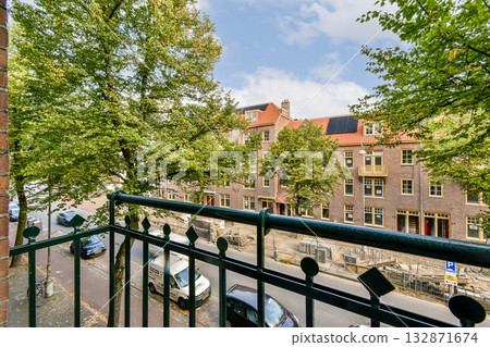 A picturesque street scene featuring lush green trees alongside historic buildings, creating a vibrant urban atmosphere. The charming architecture adds character to the view. A picturesque street scene featuring lush green trees alongside historic buildings, creating a vibrant urban atmosphere. The charming architecture adds character to the view. 132871674