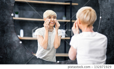 Skincare. Middle-Aged Lady Removing Makeup With Cotton Pads Caring For Face Skin Standing In Bathroom. Selective Focus 132871929