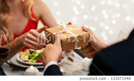 Romantic Couple Exchanging Gifts While Celebrating Valentine's Day At Dinner In Restaurant, Selective Focus, Closeup Romantic Couple Exchanging Gifts While Celebrating Valentine's Day At Dinner In Restaurant, Selective Focus, Closeup 132871946