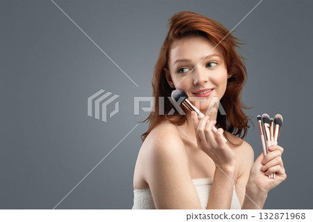 Beauty And Makeup. Red-Haired Girl Posing Holding Cosmetic Brushes Looking Aside Over White Background. Make-Up Advertisement Banner. Studio Shot, Panorama With Copy Space Beauty And Makeup. Red-Haired Girl Posing Holding Cosmetic Brushes Looking Aside Over White Background. Make-Up Advertisement Banner. Studio Shot, Panorama With Copy Space 132871968