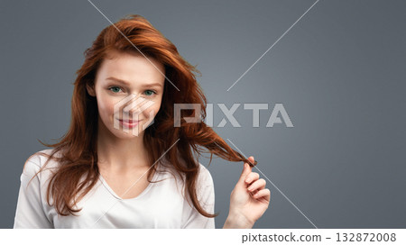 Haircare. Ginger-Haired Girl Posing Touching Loose Healthy Red Hair Smiling To Camera Posing Standing Over White Studio Background. Beauty Portrait, Hairstyle, Hair Dye And Care Concept 132872008
