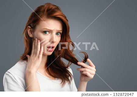Hair Problems. Red-Haired Girl Touching Dry Hair Having Split Ends Issue Posing Standing Over White Studio Background, Looking At Camera. Split-Ends Treatment And Haircare Concept Hair Problems. Red-Haired Girl Touching Dry Hair Having Split Ends Issue Posing Standing Over White Studio Background, Looking At Camera. Split-Ends Treatment And Haircare Concept 132872047