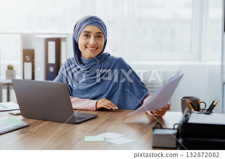 Entrepreneurship For Islamic Women. Portrait of happy muslim businesswoman in hijab with papers at office workplace, copy space Entrepreneurship For Islamic Women. Portrait of happy muslim businesswoman in hijab with papers at office workplace, copy space 132872082