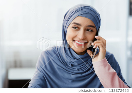 Phone Call. Smiling Muslim Woman In Hijab Talking On Cellphone And Looking Away, Closeup, Copy Space Phone Call. Smiling Muslim Woman In Hijab Talking On Cellphone And Looking Away, Closeup, Copy Space 132872433