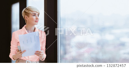 Successful Business Lady Holding Financial Report Standing Looking Out Of Window In Modern Office. Copy Space Successful Business Lady Holding Financial Report Standing Looking Out Of Window In Modern Office. Copy Space 132872457