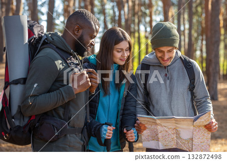 Multiracial friends with backpacks looking at map, hiking in autumn countryside 132872498