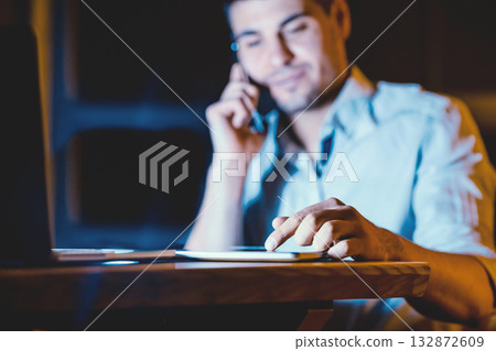 Unrecognizable Businessman Using Digital Tablet And Business Application Talking On Cellphone Working Indoors At Night. Selective Focus 132872609