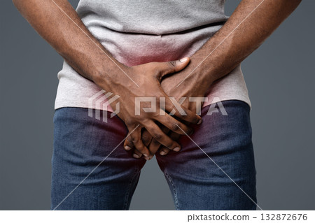 Cropped of afro man holding his groin over white background. Men's health, impotence in young age Cropped of afro man holding his groin over white background. Men's health, impotence in young age 132872676