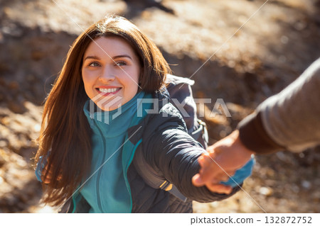 Portrait of happy young woman outstretching hand to man while hiking at forest Portrait of happy young woman outstretching hand to man while hiking at forest 132872752