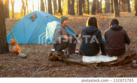 Active rest. Back view of three friends camping in autumn forest, enjoying sunset, free space 132872785