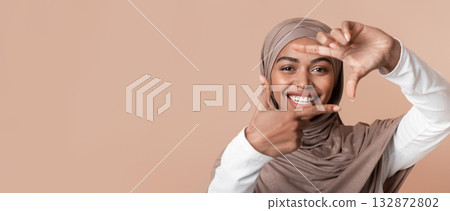Happy Black Muslim Girl In Headscarf Making Frame With Fingers, Capturing Photo, Framing Face, Standing Over Yellow Background, Closeup Happy Black Muslim Girl In Headscarf Making Frame With Fingers, Capturing Photo, Framing Face, Standing Over Yellow Background, Closeup 132872802
