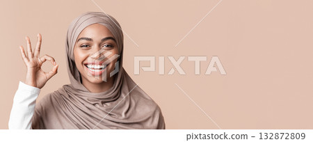It's OK. Closeup portrait of joyful black muslim girl in hijab gesturing okay sign and sincerely laughing over yellow background It's OK. Closeup portrait of joyful black muslim girl in hijab gesturing okay sign and sincerely laughing over yellow background 132872809