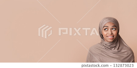Portrait of doubtful black muslim woman in headscarf biting lip and looking away at free space over yellow background, unsure about something Portrait of doubtful black muslim woman in headscarf biting lip and looking away at free space over yellow background, unsure about something 132873023